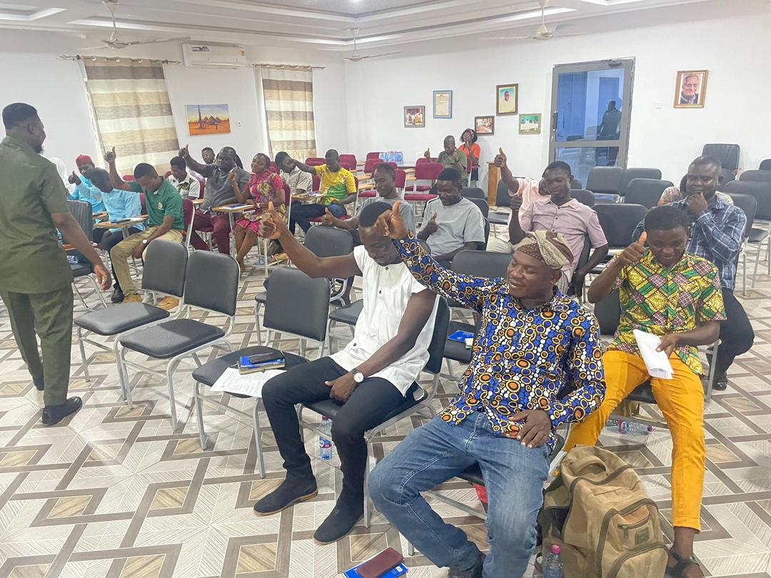 Workshop participants giving thumbs-up in a training hall